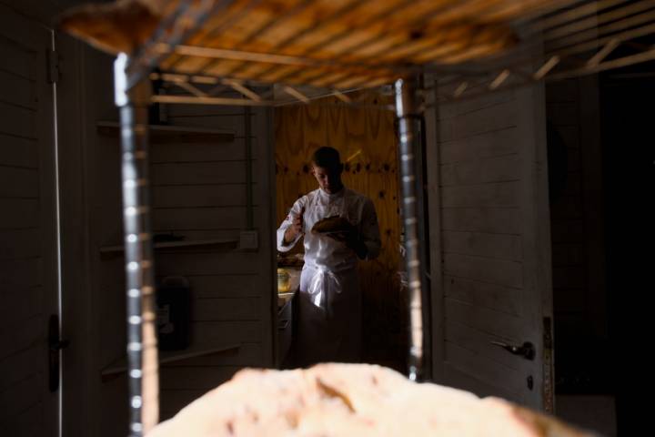 Nico con un pan al fondo de la habitación.