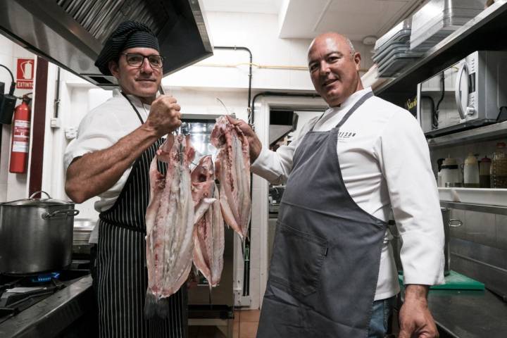 Nelson posa, junto a uno de sus trabajadores, en su cocina con varias lubinas abiertas