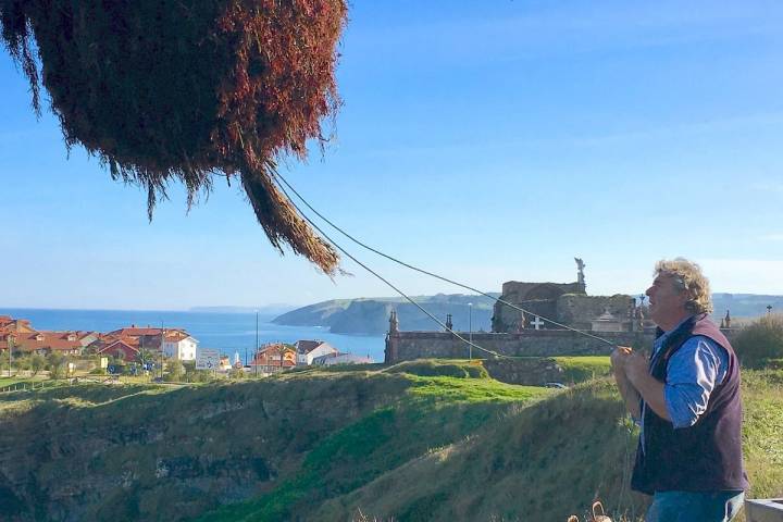 Juan vacía una cesta de “caloca” en la pluma de Comillas, con el cementerio y su Ángel Exterminador de fondo.