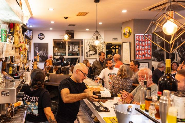 El interior del 'Baste' lleno de gente, con un camarero sirviendo vino detrás de la barra.