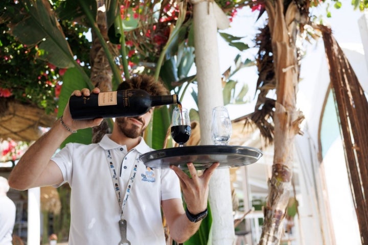 Camarero del chiringuito La Manuela sirviendo una copa de Pedro Ximenez.
