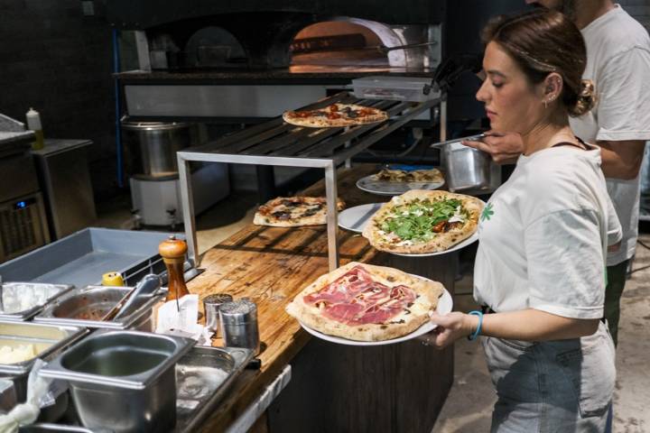 Una camarera sujeta dos pizzas antes de sacarlas a las mesas.