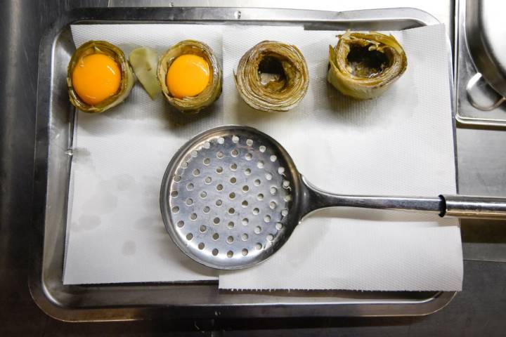 Bandeja de metal con alcachofa, huevo y una paleta.