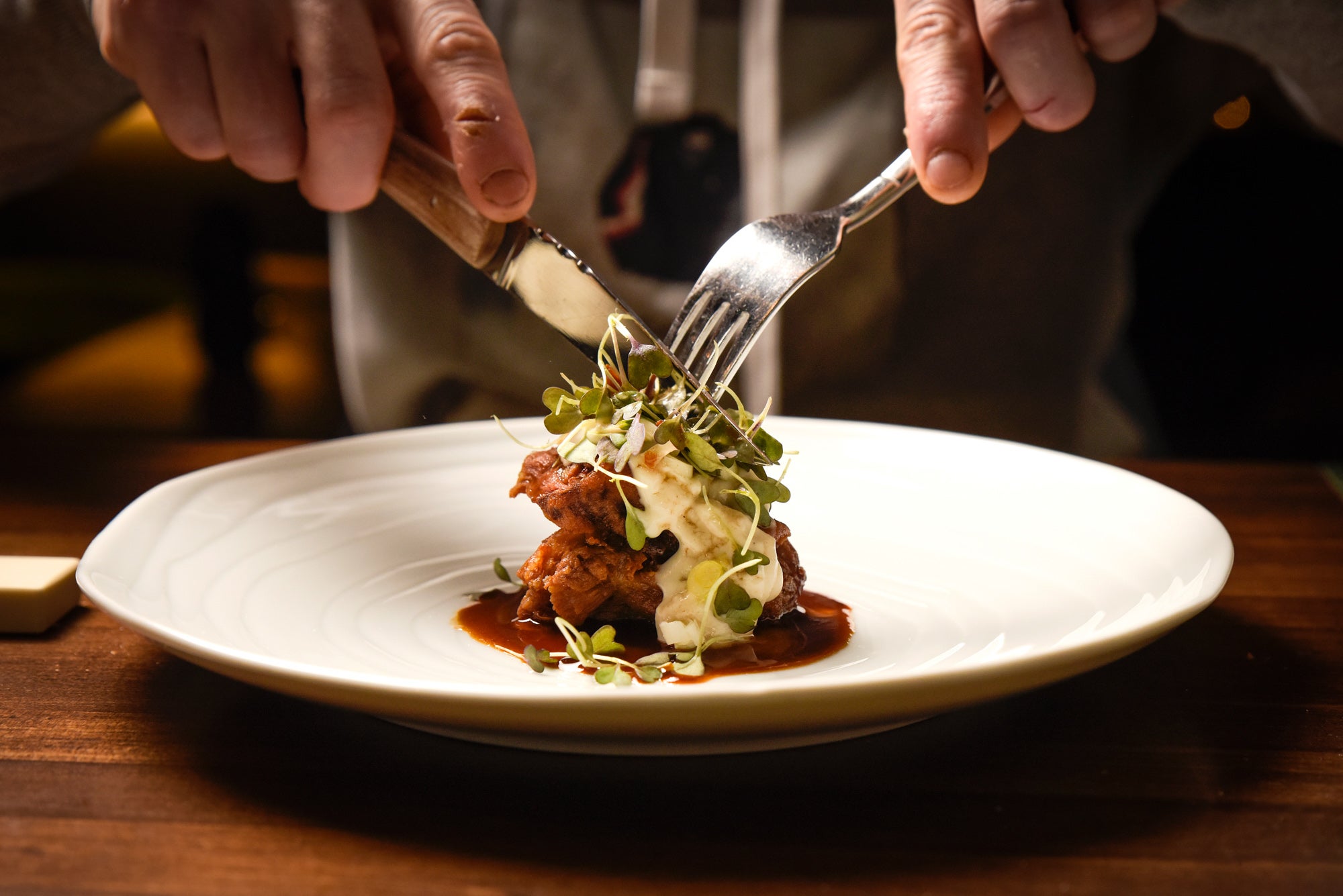 Cochifrito con hierba, mostaza y su jugo en emulsión.