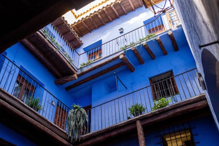 Patio interior azul lleno de plantas.