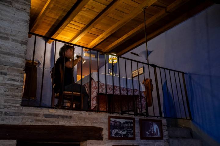 Un hombre comiendo en una mesa en un balcón interior.