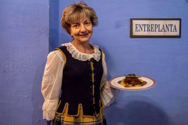 Olga con un plato en la mano y un vestuario tradicional.