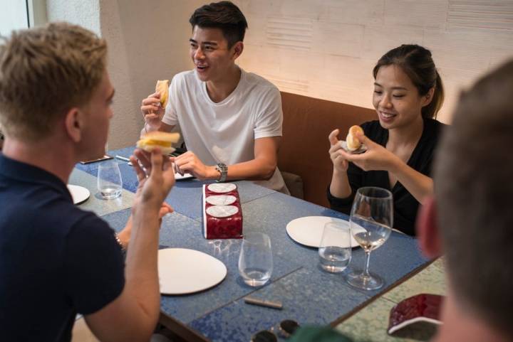 Un grupo de jóvenes extranjeros con caras de felicidad mientras toman un postre