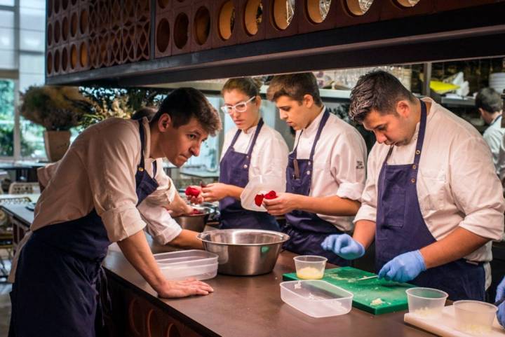 tres cocineros deshojan rosas en la cocina abierta de Disfrutar