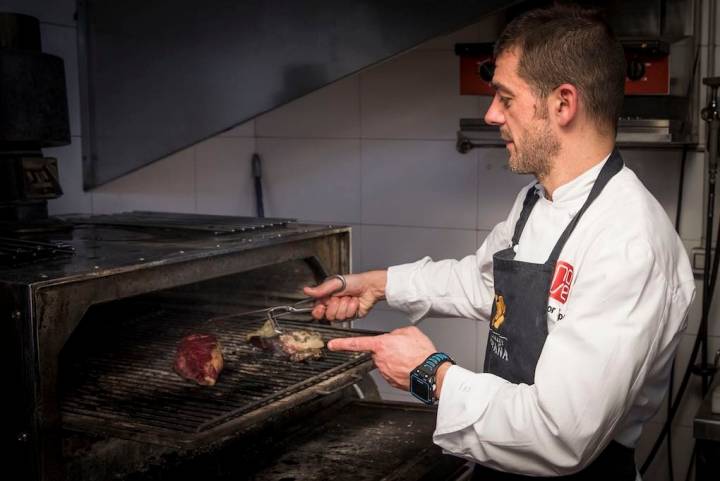 Héctor López cocinando carne de buey a la brasa