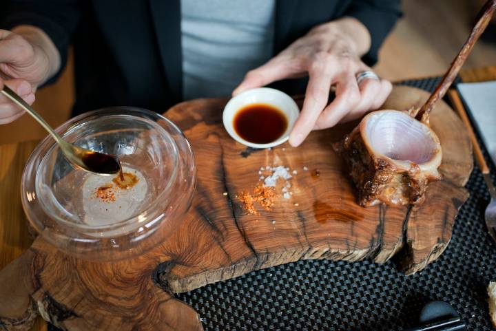 Un comensal mezcla en la mesa el tuétano con la salsa secreta de jengibre.