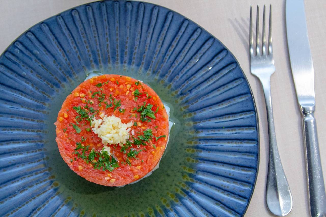 Lascas de bacalao macerado en aceite de oliva con tomate rallado y vinagreta de ajo conforman uno de los platos estrella de 'La Taberna de Almodóvar'.