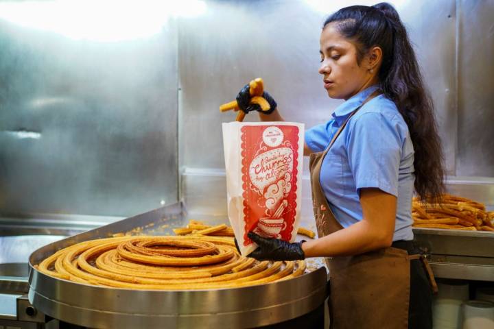 Una empleada de El Castillo empaqueta unos churros para llevar.