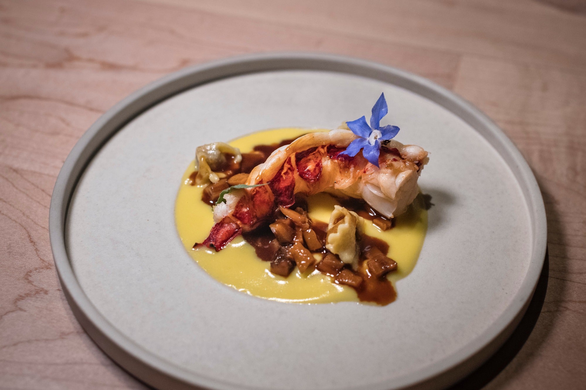 Bogavante a la brasa con plin de guiso de gallo y salsa de ají amarillo.