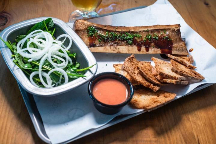 Tuétano a la parrilla con tostas de pan con tomate y ensalada de hierbas y limón.