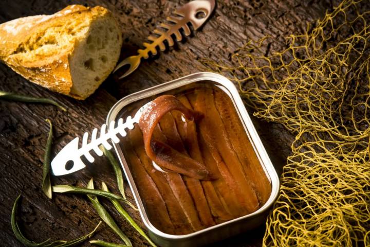 Salted anchovy fillets in olive oil tin can. Artisan anchovies from Cantabrian sea salting with olive oil on a rustic wooden table