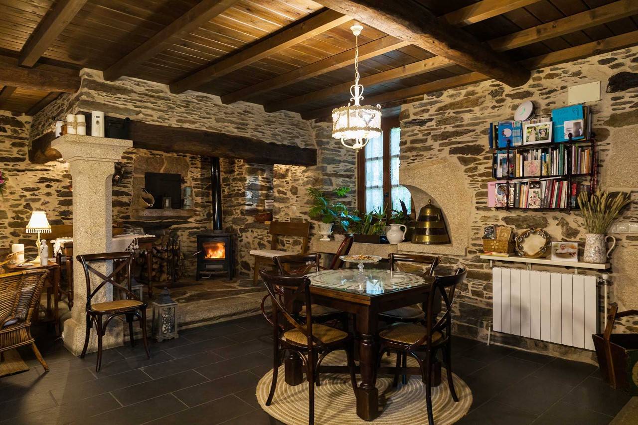 Salón interior de la 'Casa rural Antón Veirás' con libros y chimenea.