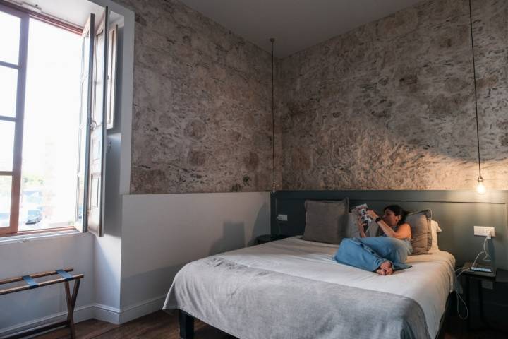 Mujer leyendo en la cama de una de las habitaciones.