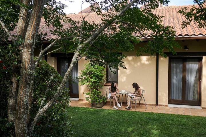 Dos mujeres están sentadas en la mesita de la terraza de una de las habitaciones.