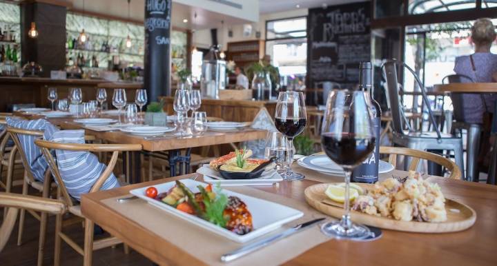 Restaurante del Hostal Cuba con mesas con comida y vinos