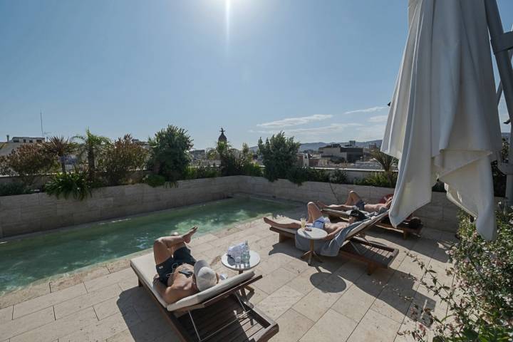 Varias personas toman el sol en la piscina en el rooftop