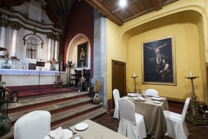 Vista de un par de mesas del restaurante, ubicado en la antigua capilla, donde se ve el altar.