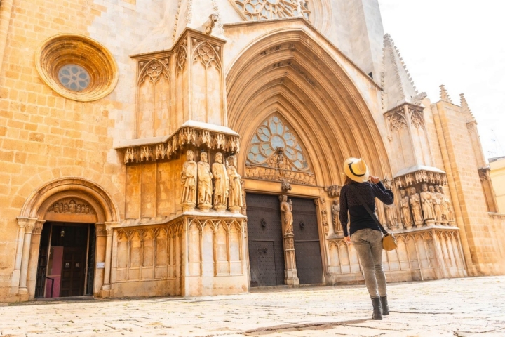 Female tourist admiring the medieval architecture of tarragona cathedral on a sunny day in catalonia