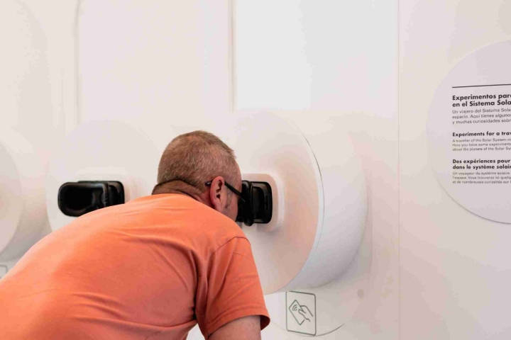 Hombre mirando por uno de los interactivos del museo.