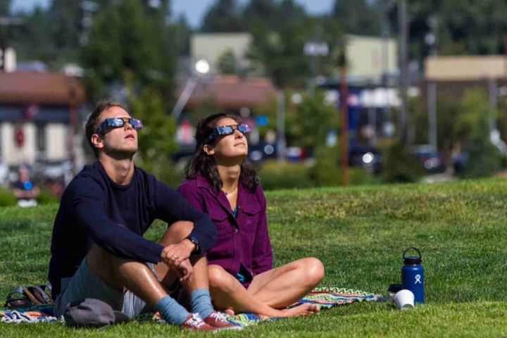 Pareja mirando al sol con gafas especiales para eclipses.