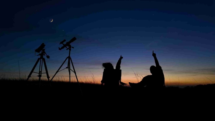 Personas que disfrutan observando el cielo con telescopios astronómicos al aire libre.