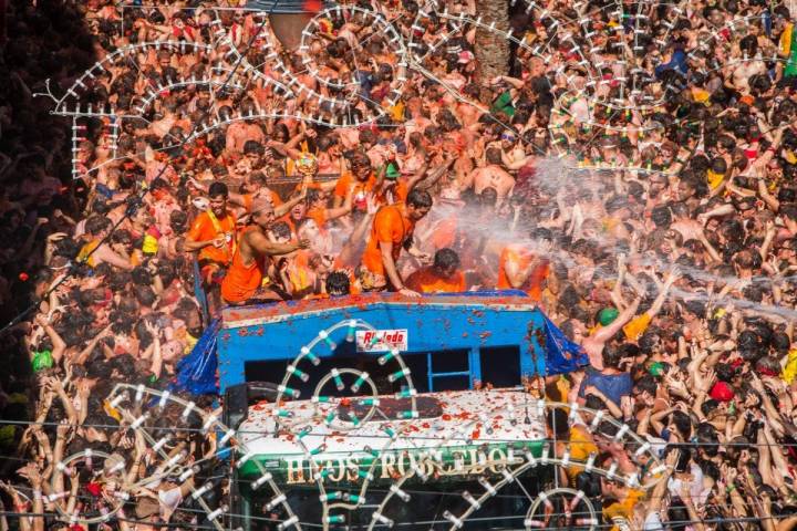 La Tomatina de Buñol comienza con el lanzamiento de tomates y chorros de agua desde los camiones.