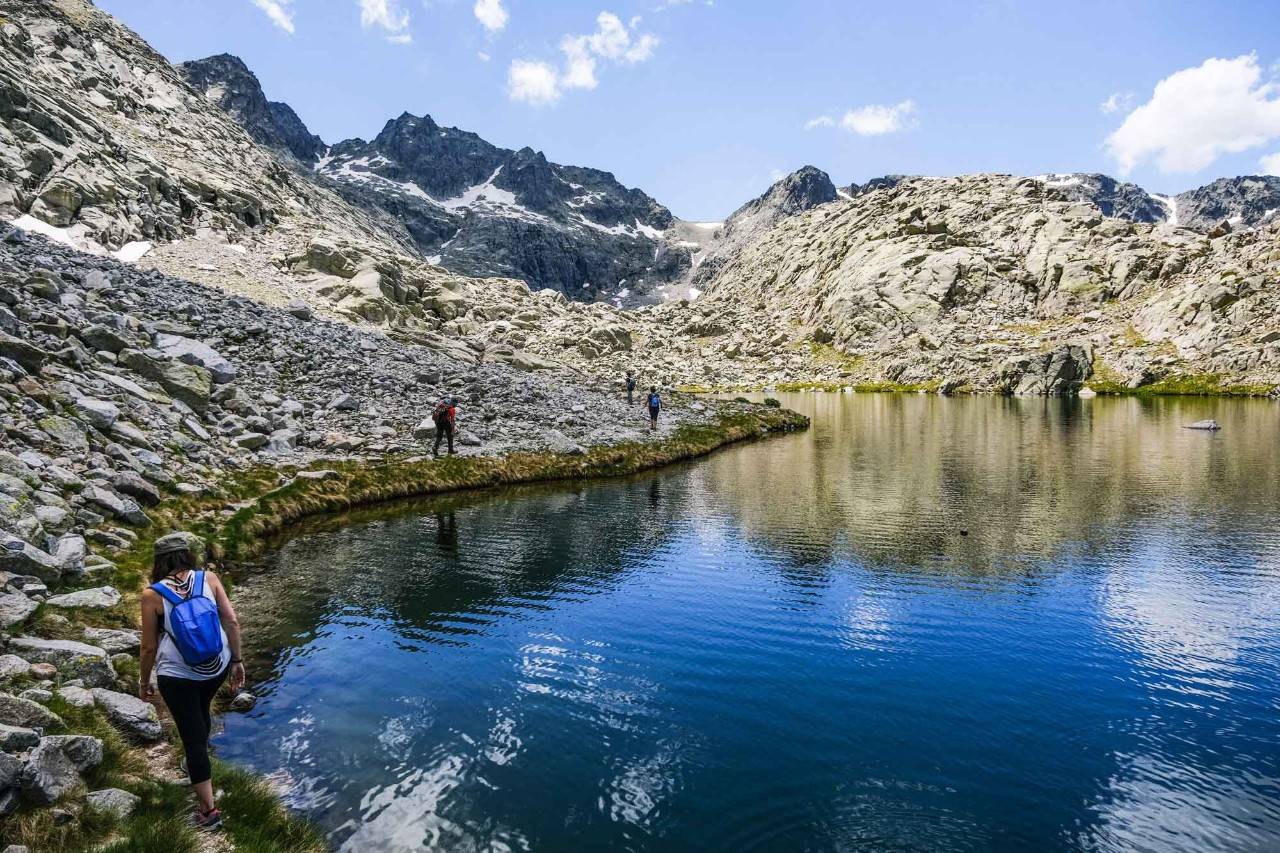 Varias personas bordean por la orilla la primera laguna, conocida como Bajera, para llegar a las otras.