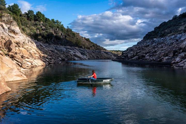 Una chica navega en barca por el embalse de Rivera de Gata.