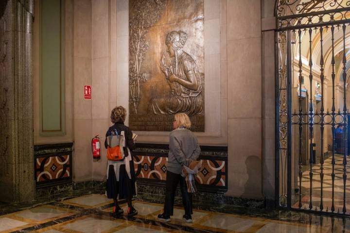 Dos mujeres contemplan el homenaje a las telefonistas antiguas en el hall del Edificio Telefónica