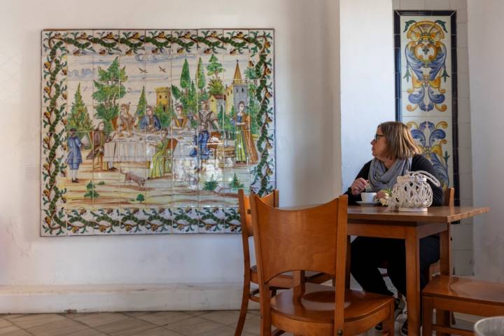 Mujer sentada en una mesa del restaurante mirando uno de los cuadros.