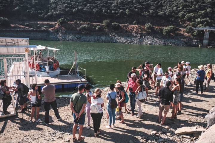 La gente espera en el embarcadero a que la tripulación termine de preparar el barco.