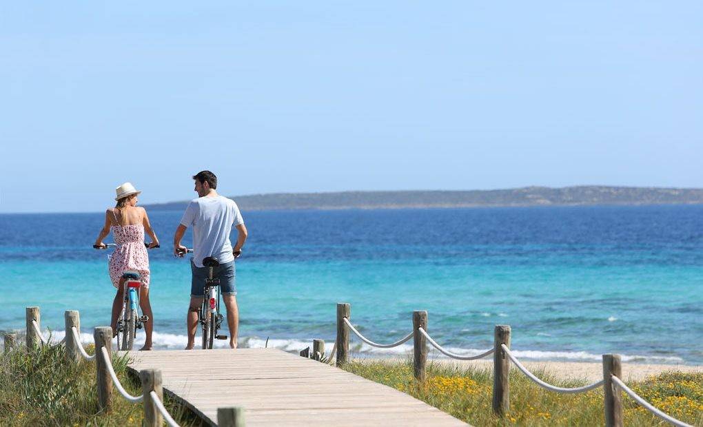 Una pareja dando un paseo con la bicicleta con el mar de fondo.