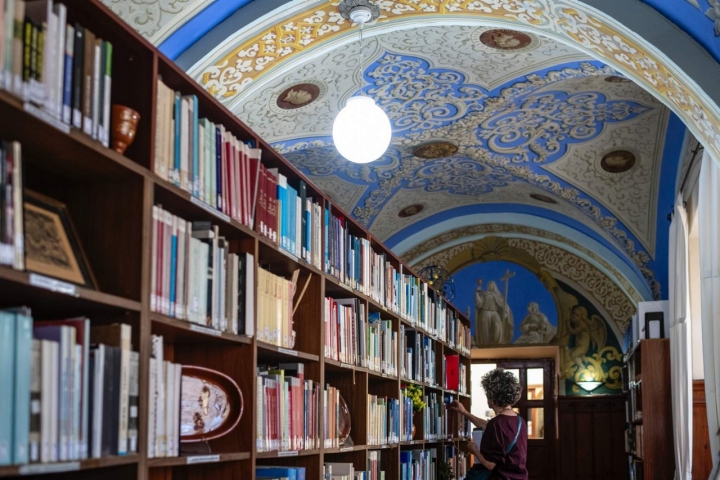 Una mujer busca entre los libros de la biblioteca del Monasterio de San Zoilo.