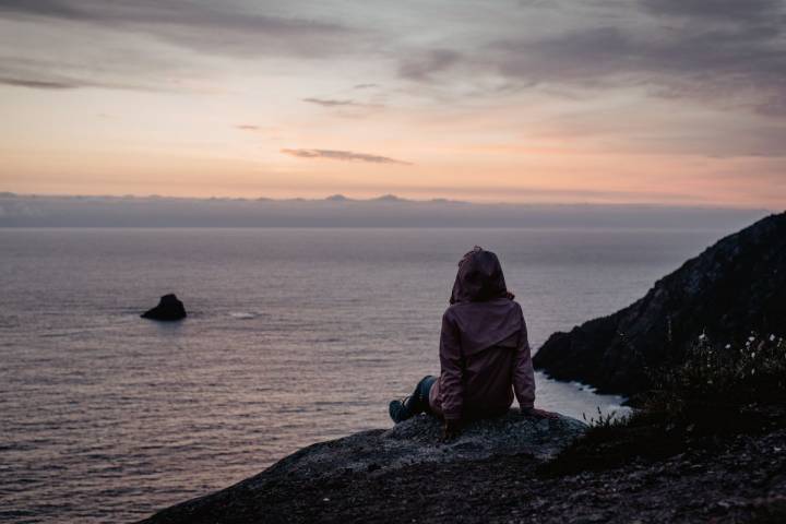 Una chica mirando el atardecer en O Camiño dos Faros (Costa da Morte, A Coruña).