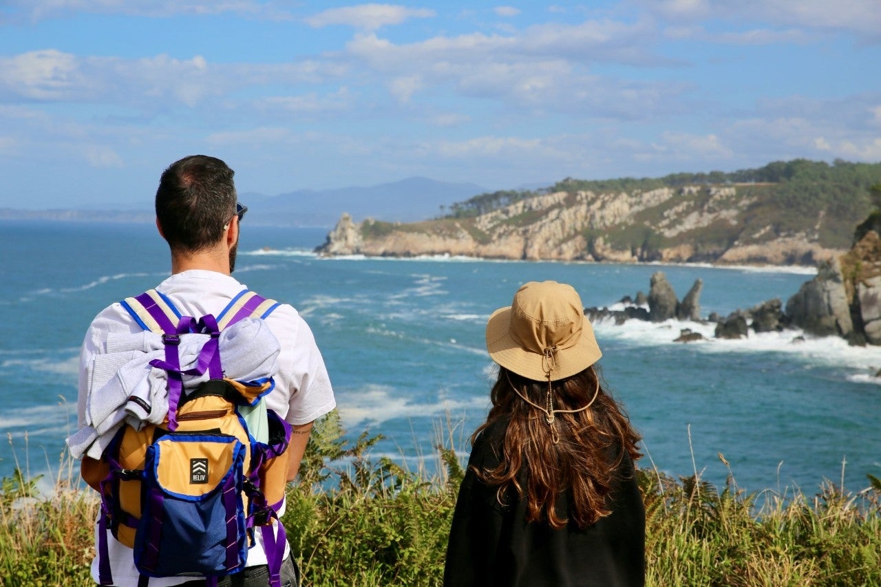 Dos senderistas se asoman a un mirador de la Senda Costa Naviega
