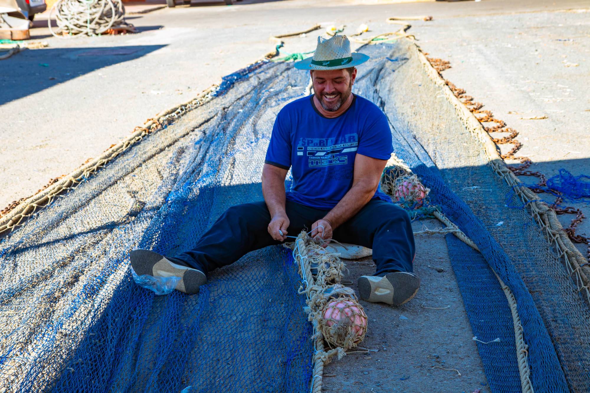 Pescador retirado arreglando redes.